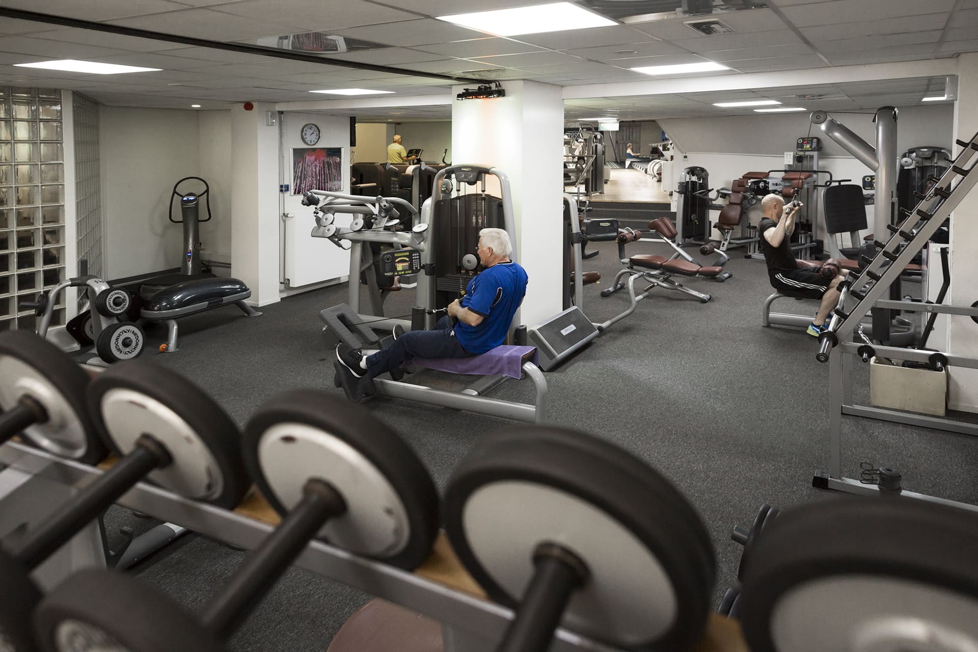 Cliënten trainen op fitnessapparatuur in de oefenzaal van de praktijk